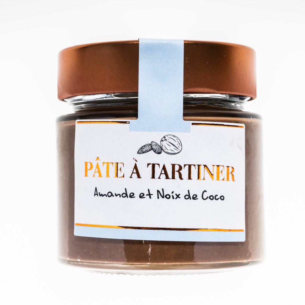 Pots de pâte à tartiner artisanale à l’amande et à la noix de coco, posés sur une table en bois.