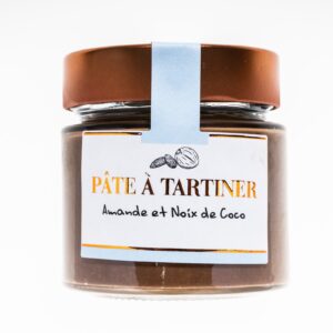 Pots de pâte à tartiner artisanale à l’amande et à la noix de coco, posés sur une table en bois.