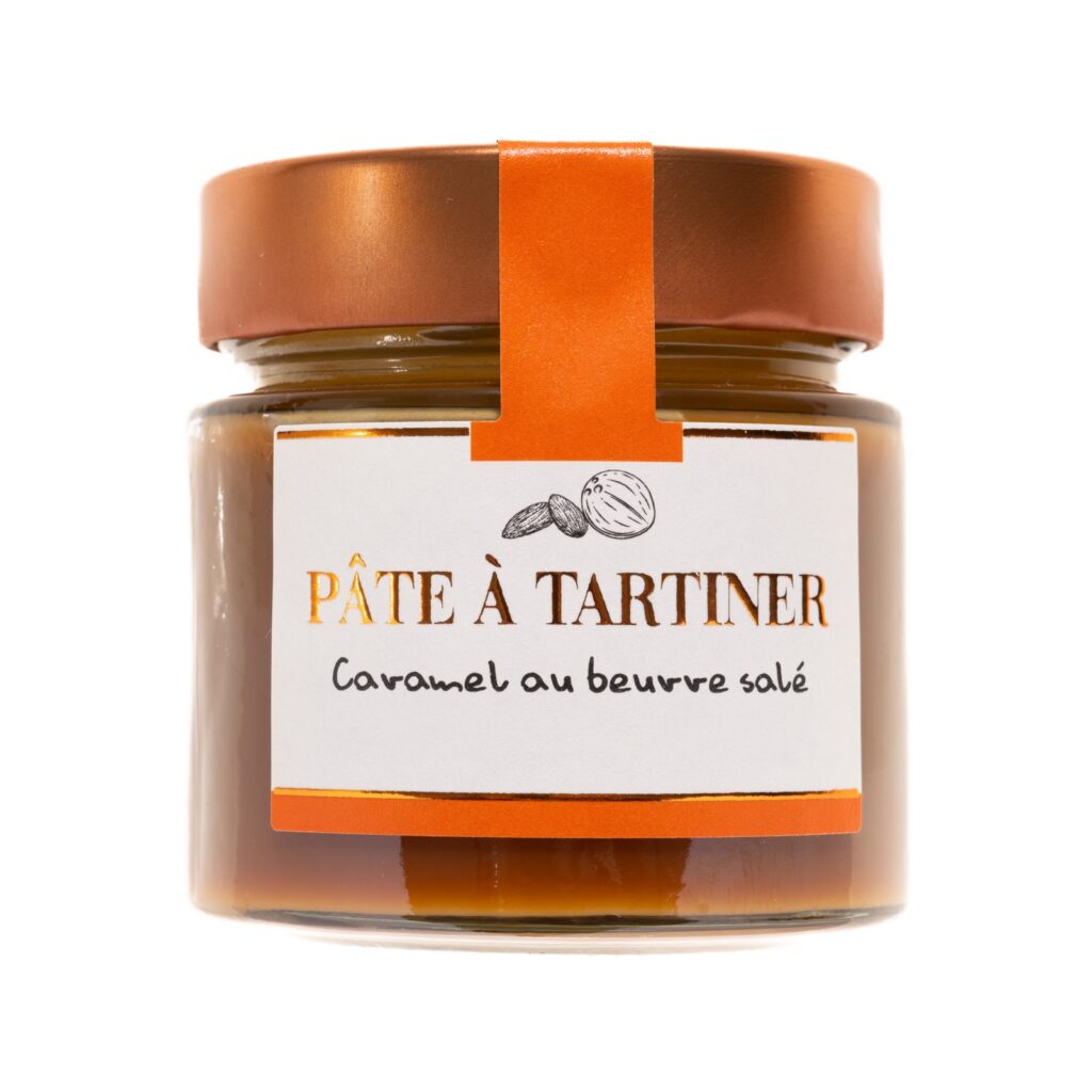 Pot de pâte à tartiner au caramel beurre salé, vu de face sur un fond en bois clair, avec couvercle doré et étiquette artisanale Papa Gâteau.