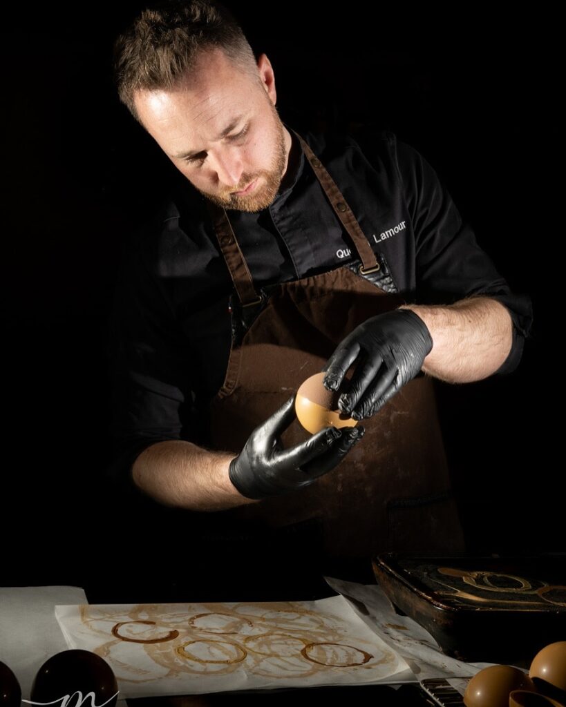 Quentin Lamour façonnant une sphère en chocolat dans son atelier.